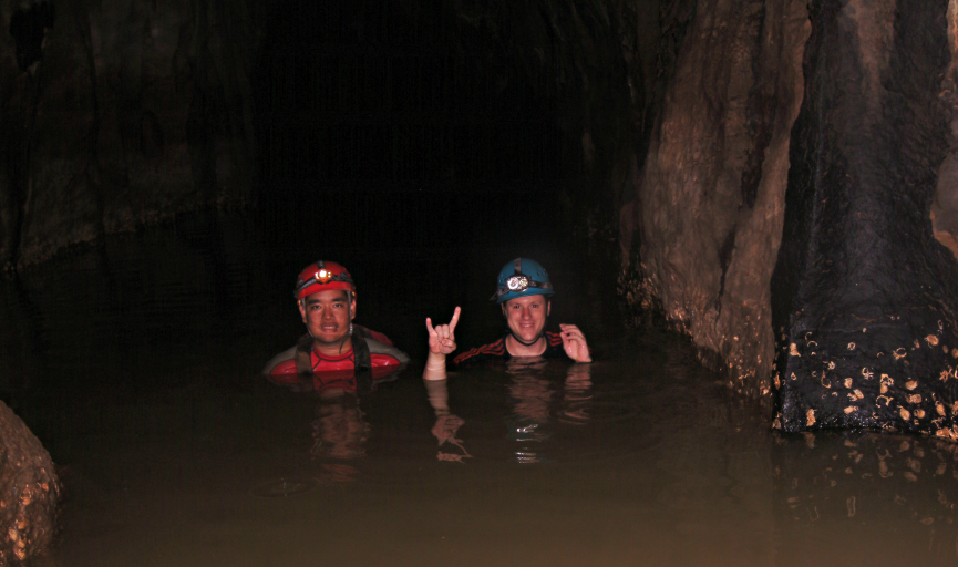 Jud Partin shows the 'hook em horns' sign in a cave in the Philippines