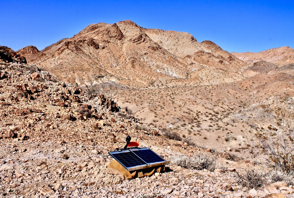 A seismic sensor facing a small mountain.