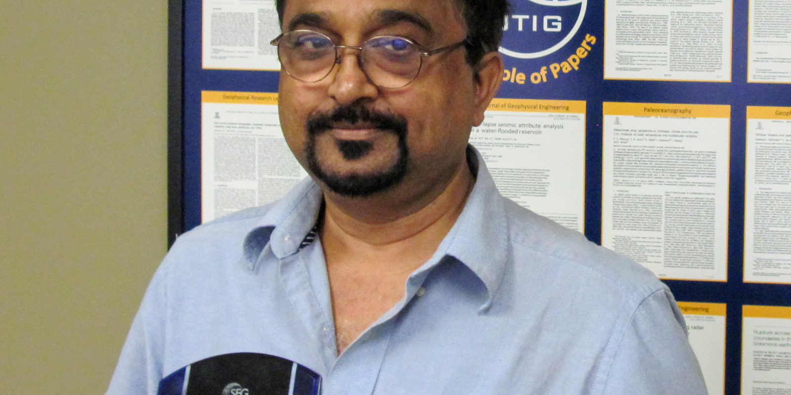 Photo of Mrinal holding two award plaques.