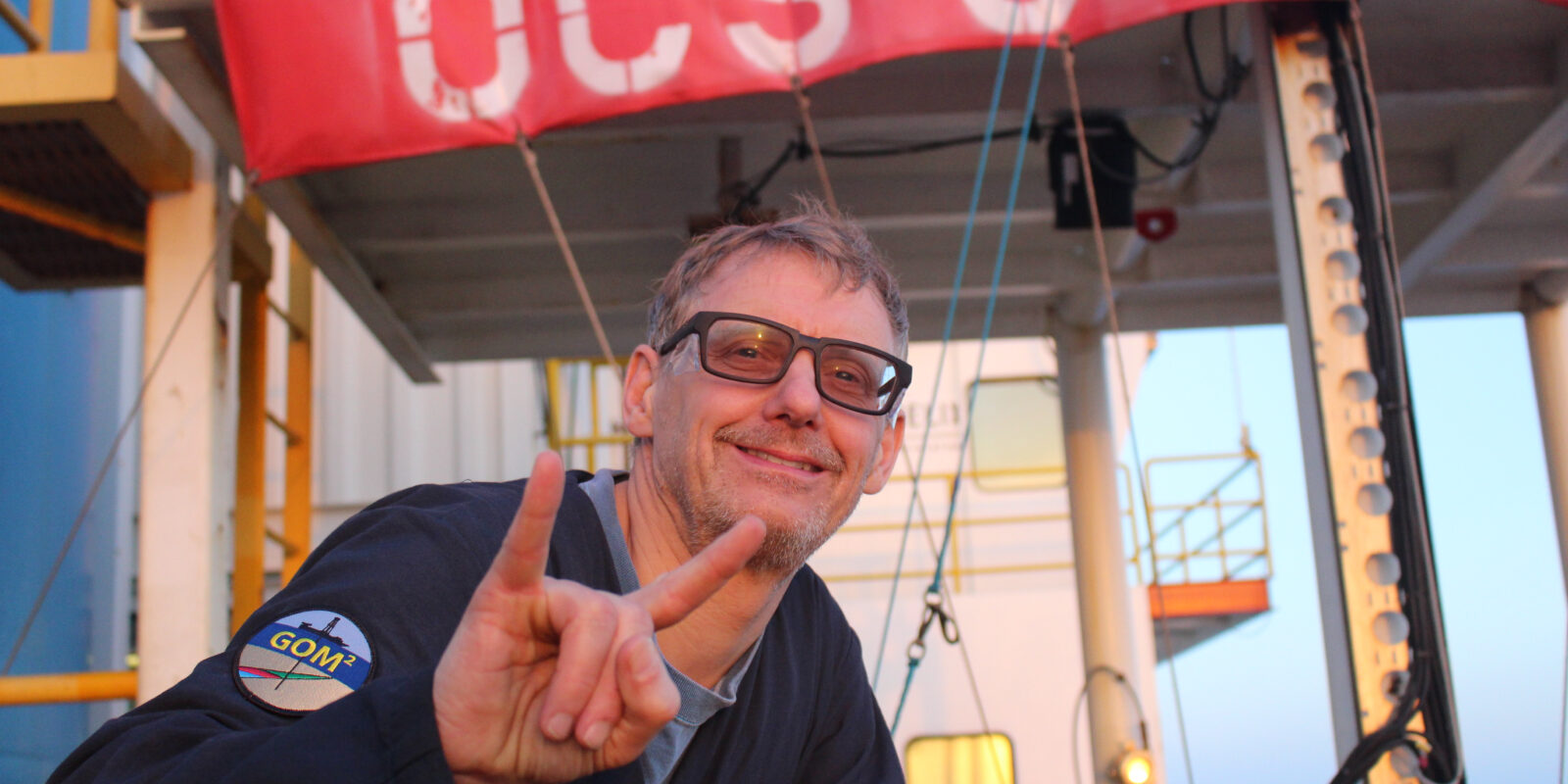 A photo of Peter Flemings with the deck of the deep-water coring vessel behind him.