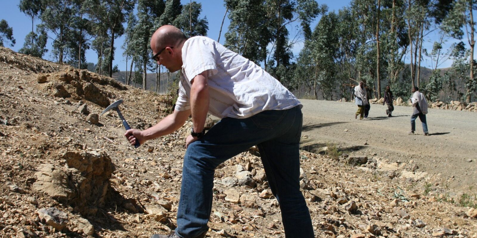 Field photo showing Thorsten Becker hitting a rock with a hammer.