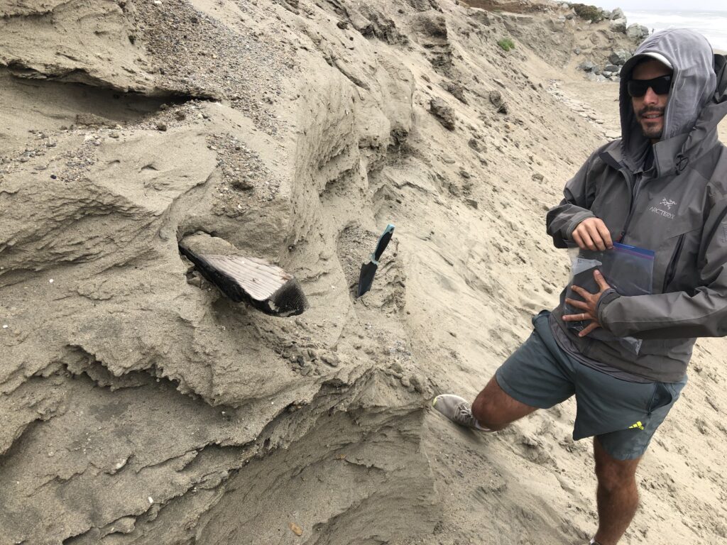 Zach standing next to a steep cut sand dune