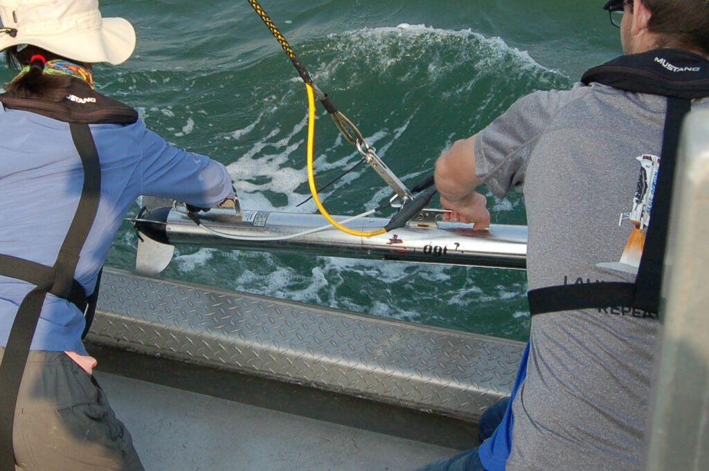 picture showing the torpedo-like sidescan sonar being lifted from the water.