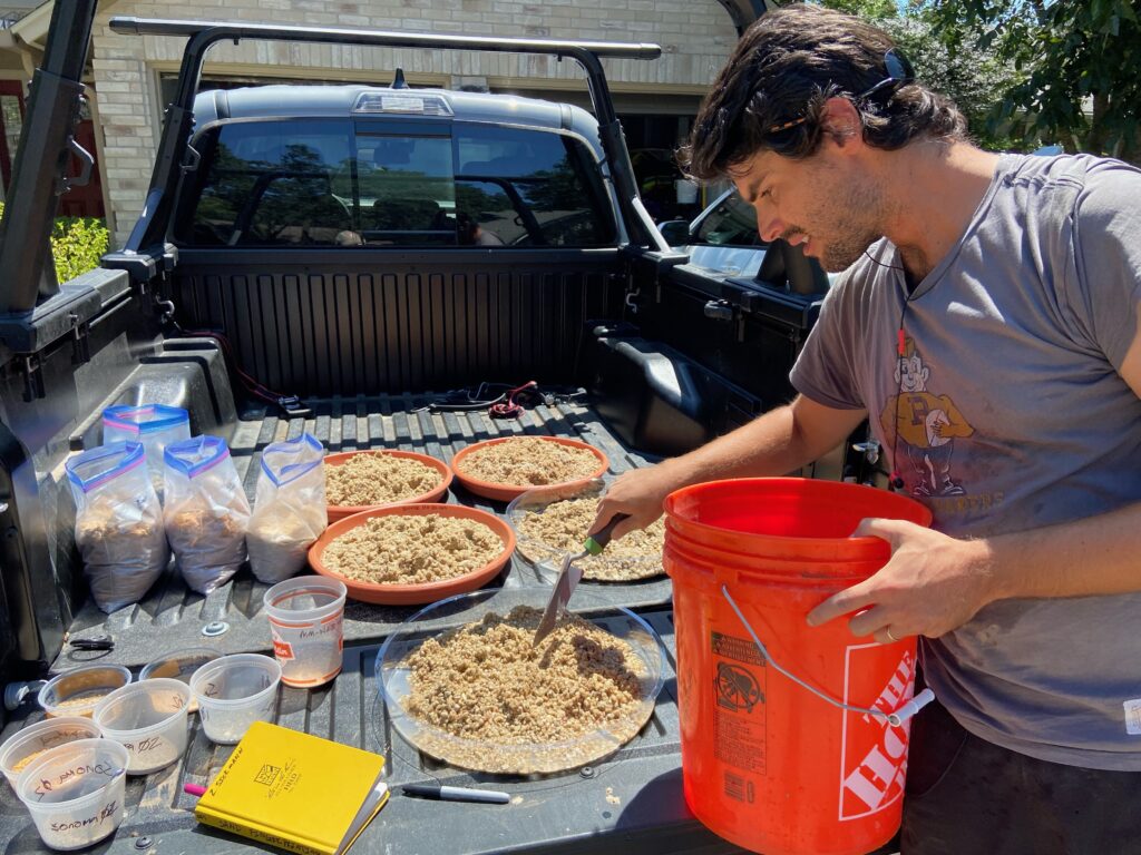 Zach and the back of a flatbead truck with equipment and samples lain out.