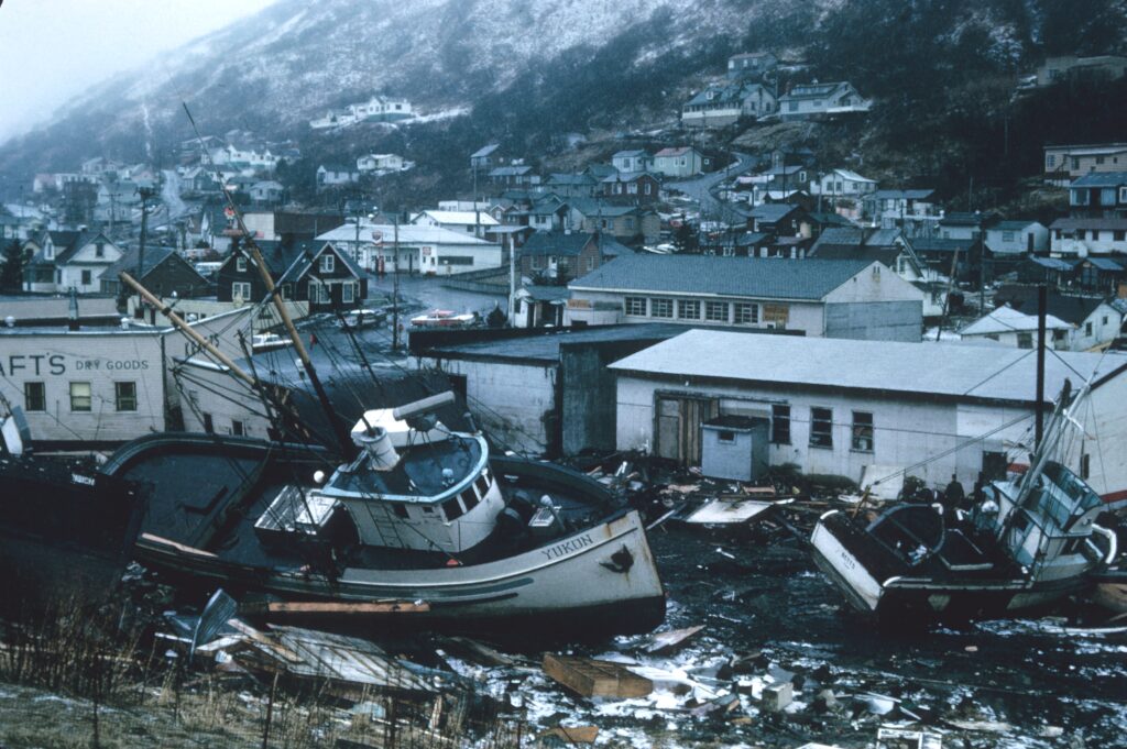 A fishing boat sits among litter strewn streets and damaged buildings..