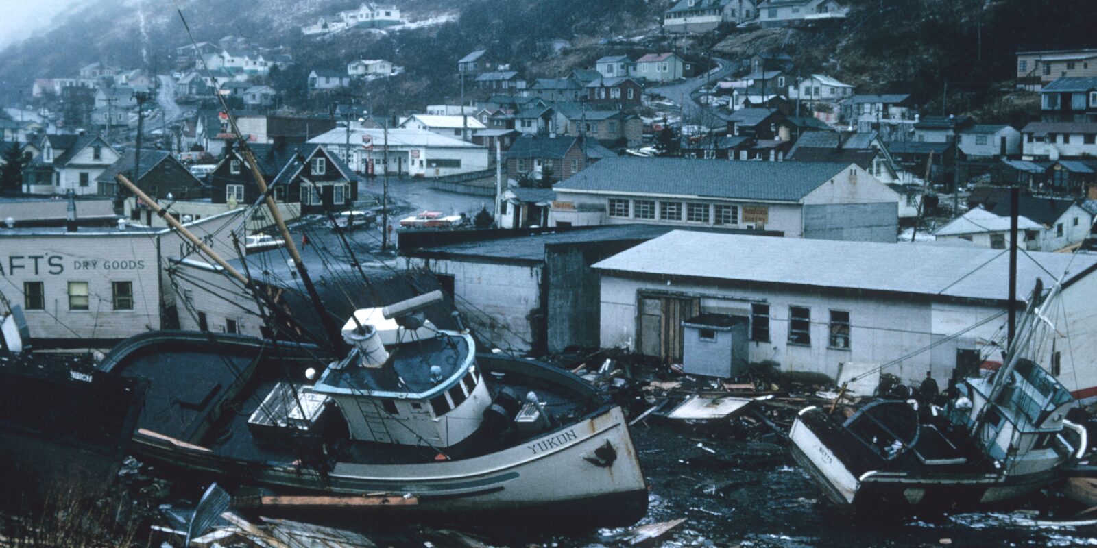 A fishing boat sits among litter strewn streets and damaged buildings..