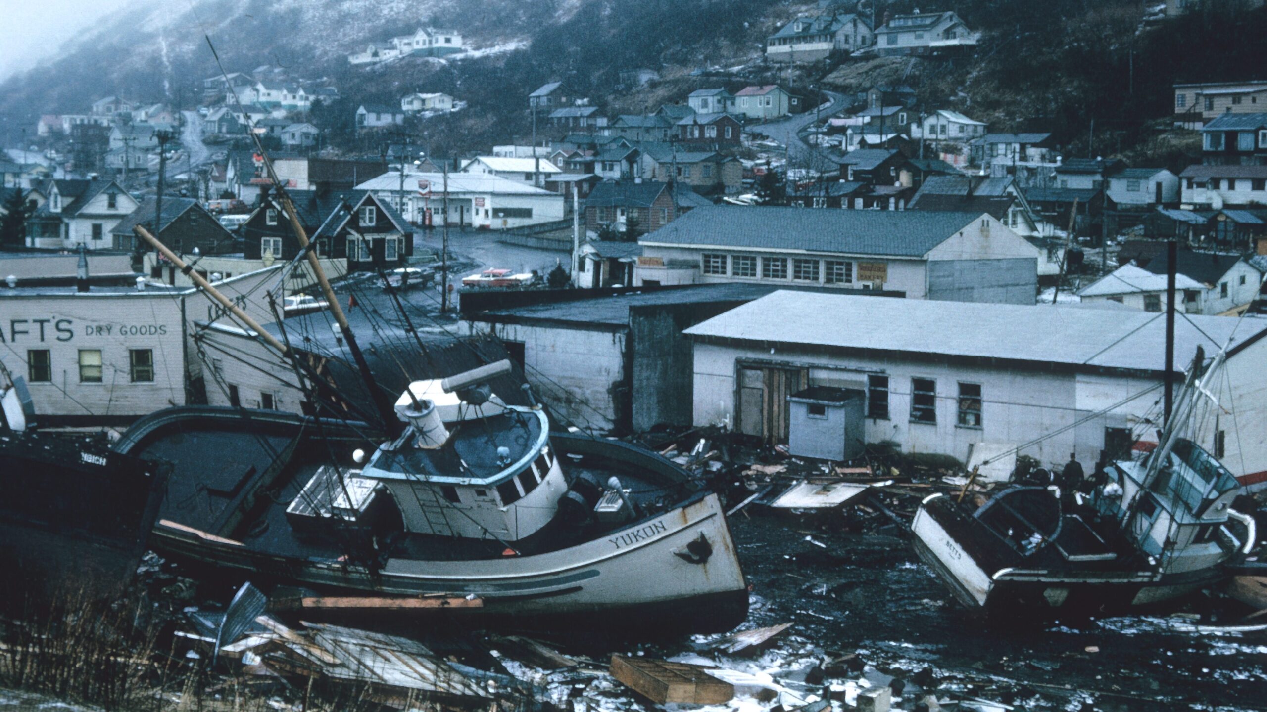 A fishing  boat sits among litter strewn streets and damaged buildings..