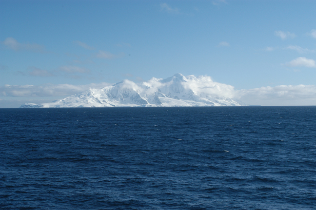 Photo of the ocean with an ice covered island  on the horizon