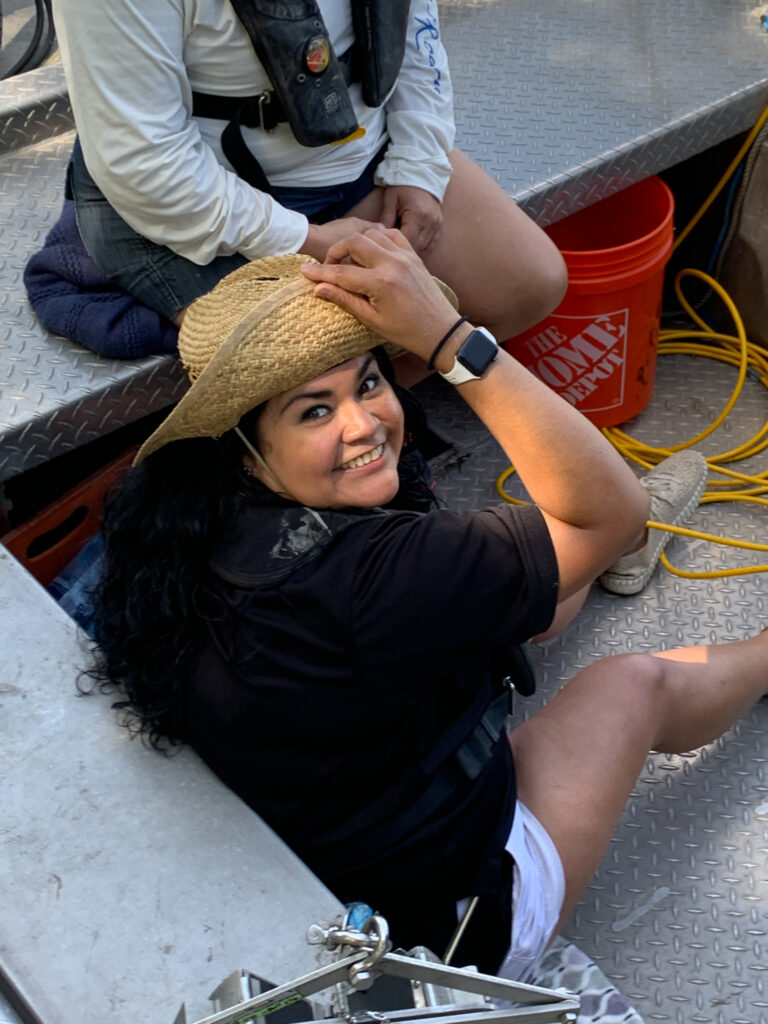 Angela sitting on the deck of the boat. She is looking up at the camera