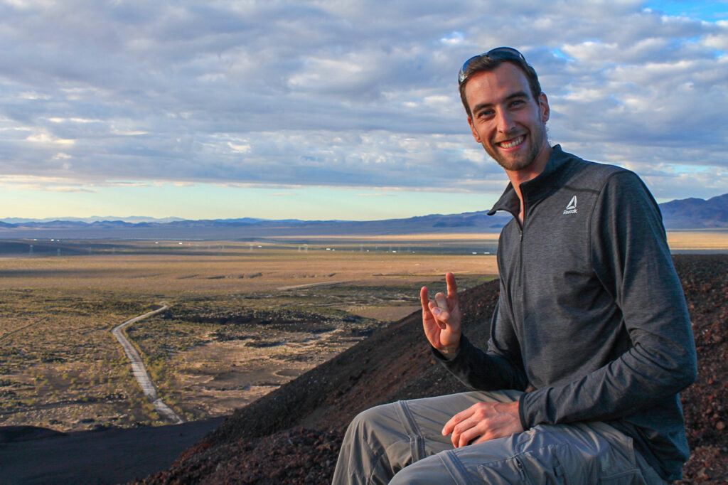 Simone flashes a longhorn at the camera. Behind him is a rocky desert landscape with mountains on the horizon