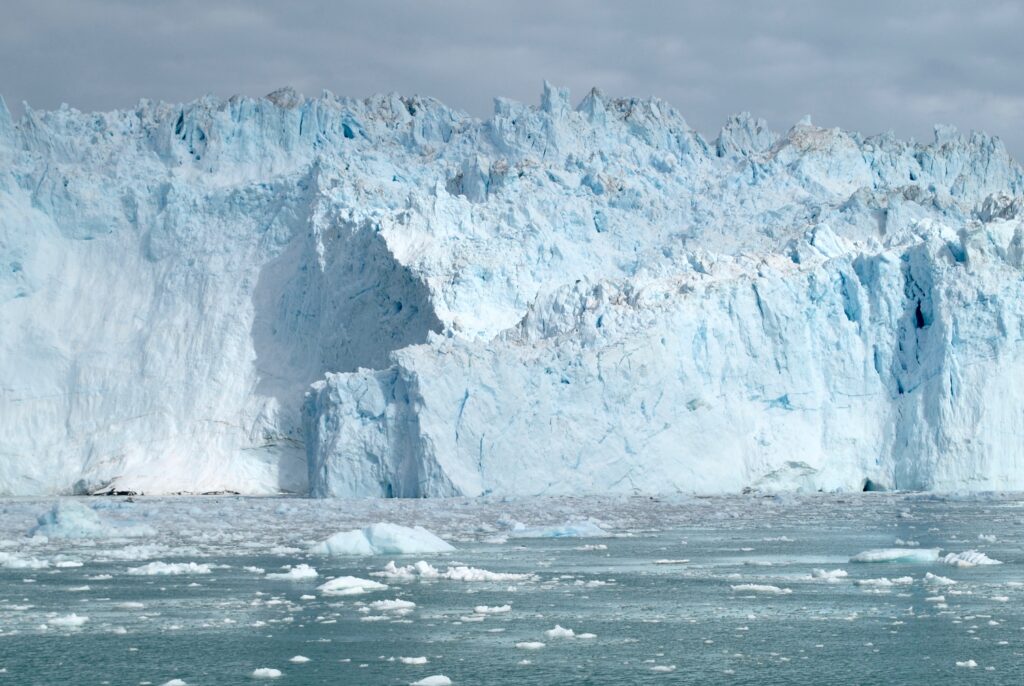 A wall of blue ice towers over the sea.