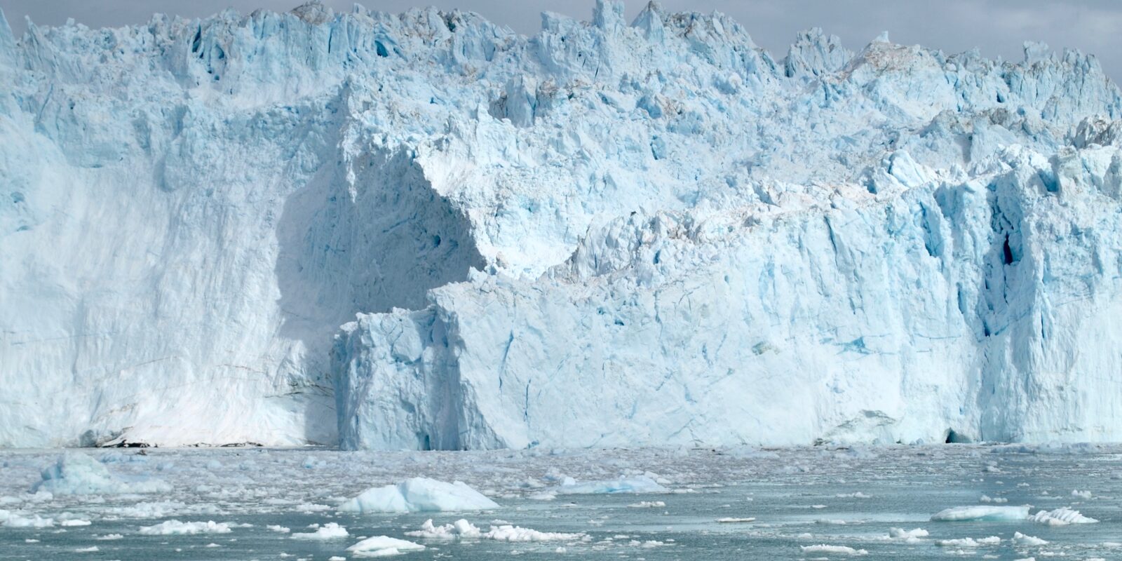 A wall of blue ice towers over the sea.