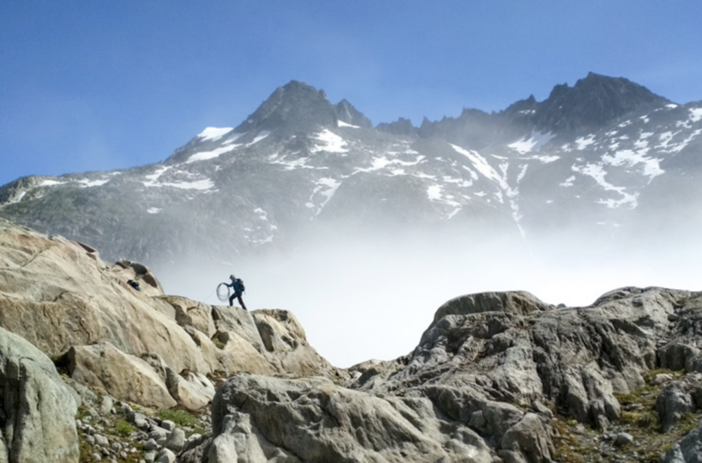 A mountaineer crosses a peak on a mountain skyline
