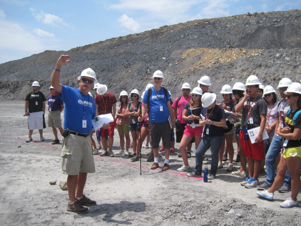 Jamie Austin is teaching a group of students outdoors a limestone ridge. Everyone wears hardhats.