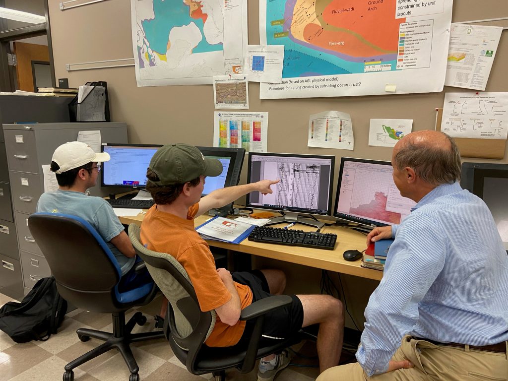 Photograph of undergraduate research assistant Jake Margoshes pointing at his screen and discussing with co-director Michael Sweet.