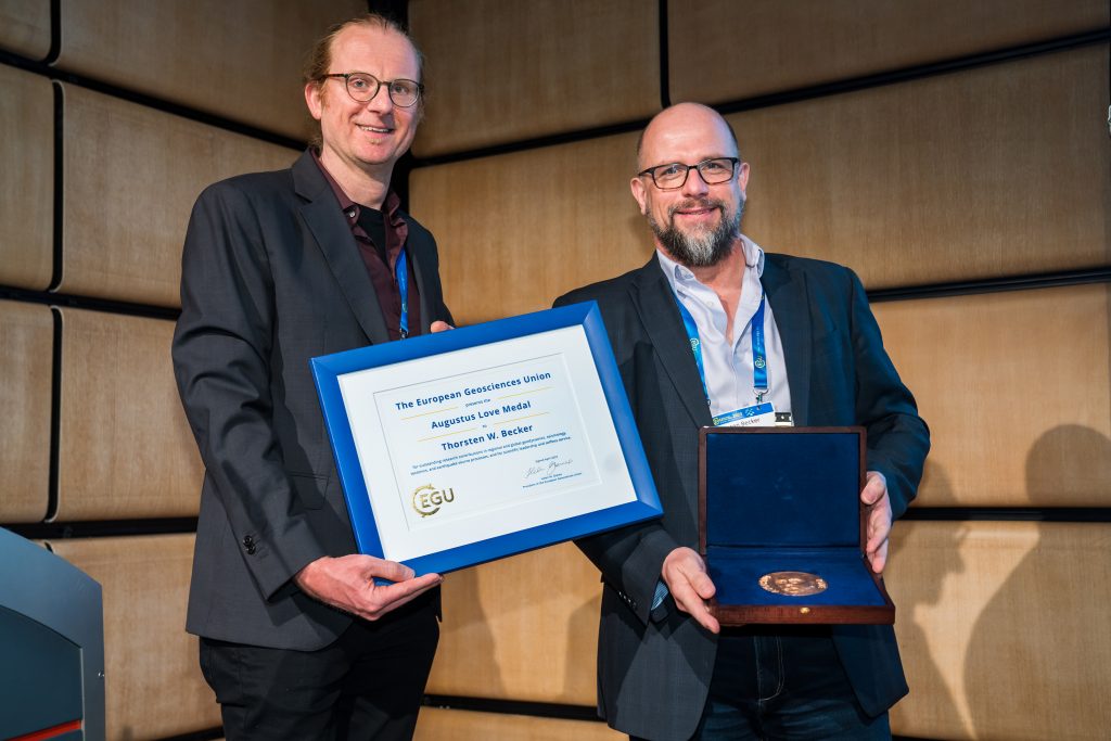 A photo of Thorsten showing his medal to the camera. Next to him Jeroen holds the accompanying certificate.
