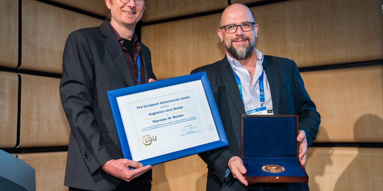 A photo of Thorsten showing his medal to the camera. Next to him Jeroen holds the accompanying certificate.