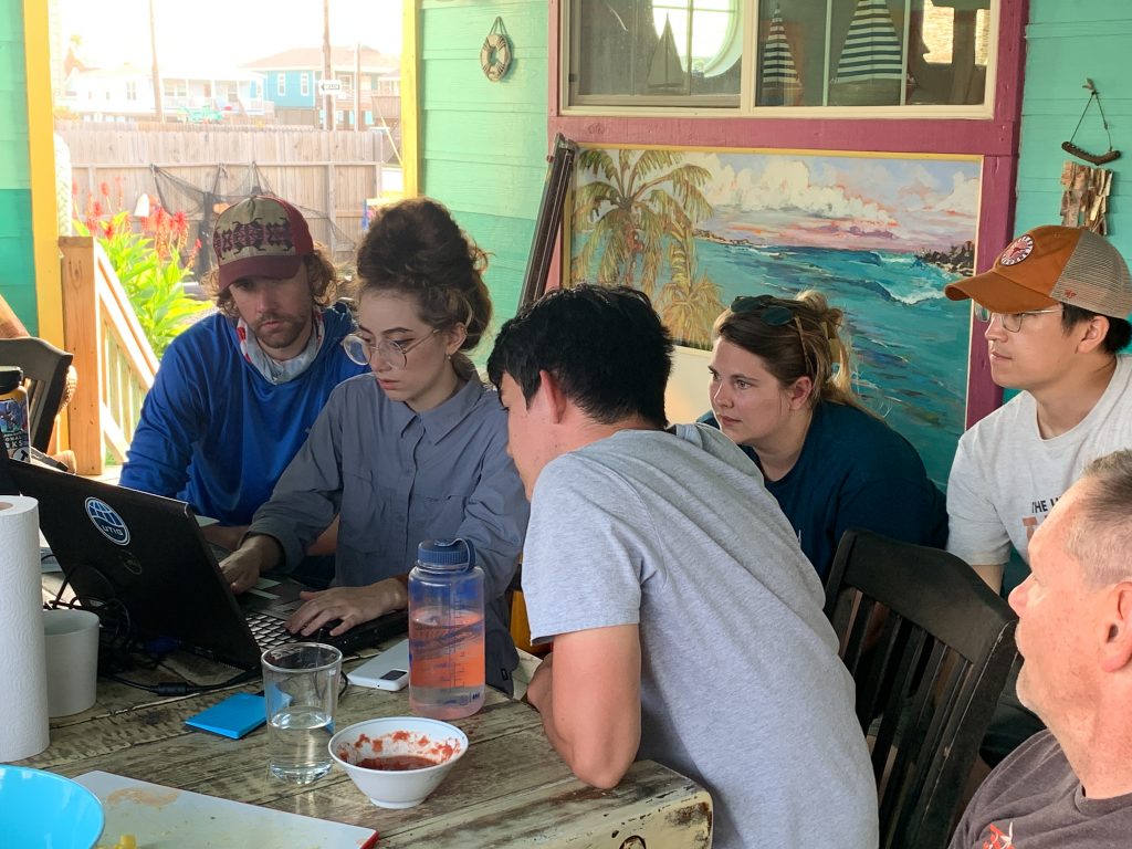 Group of students watching another student working on a laptop.