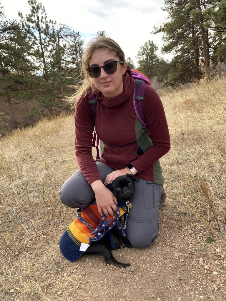 Photo of Sabrina in a field with her small dog.