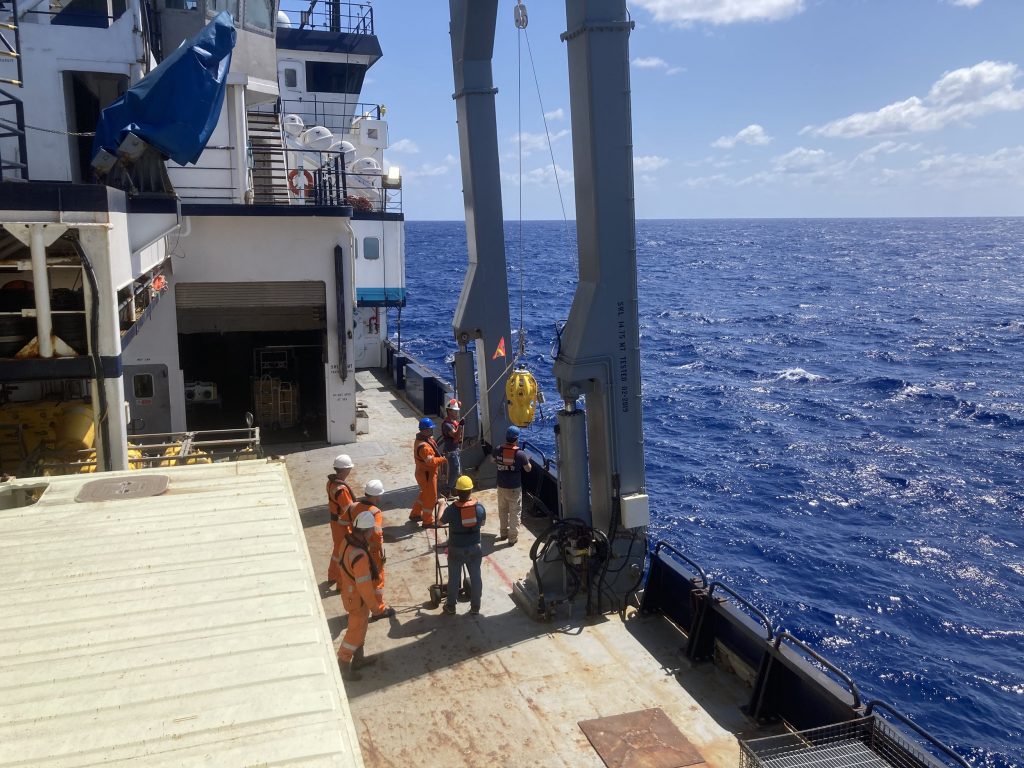 An instrument being deployed into the ocean from the side of a research vessel.