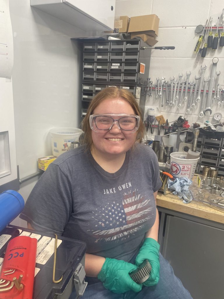 Photo of Kylie in a lab, wearing safety goggles and gloves.