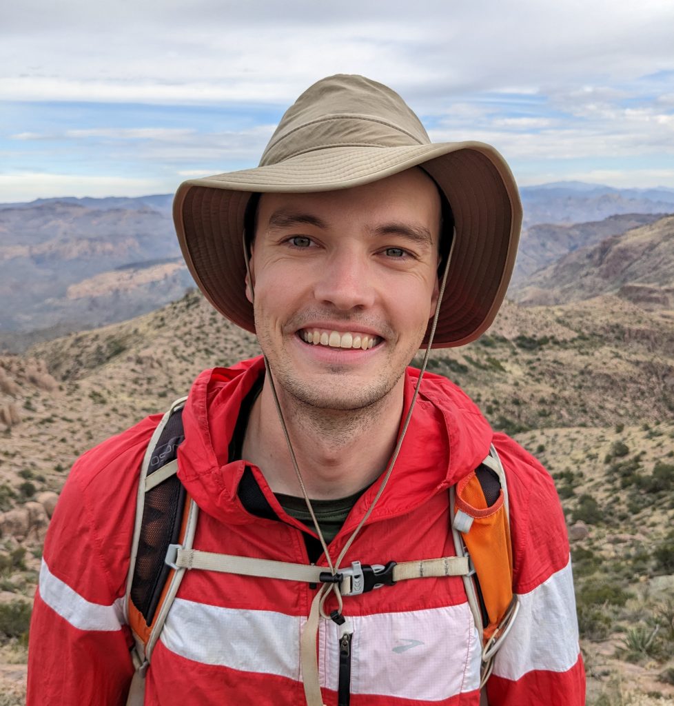 Photo of Will wearing a hat in front of a mountain landscape
