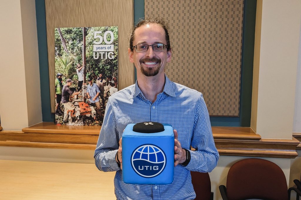 Photo of Ben Phrampus holding the UTIG cube in the seminar room.
