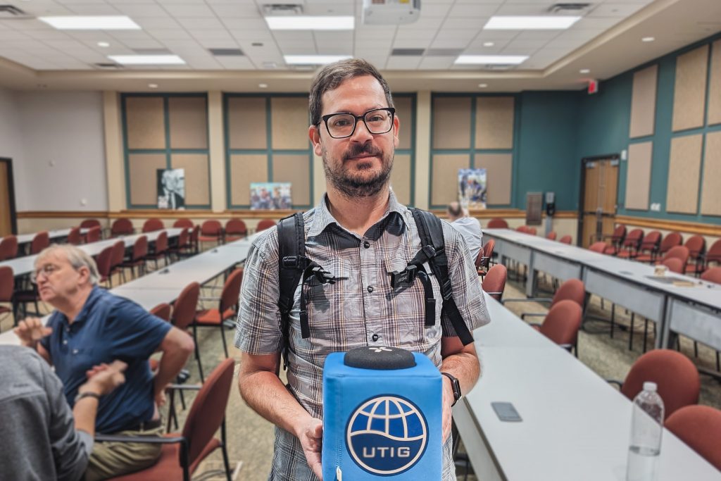 Photo of Evan Solomon holding the UTIG cube in the seminar room.