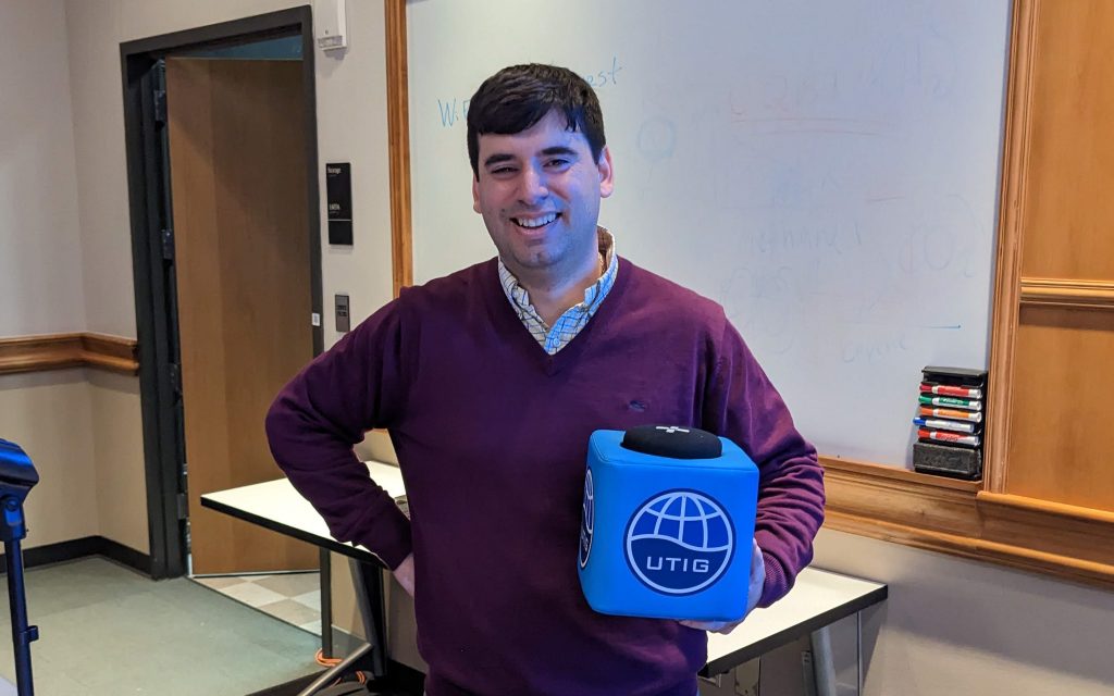 Photo of Ignacio Sepulveda holding the UTIG cube in the seminar room.
