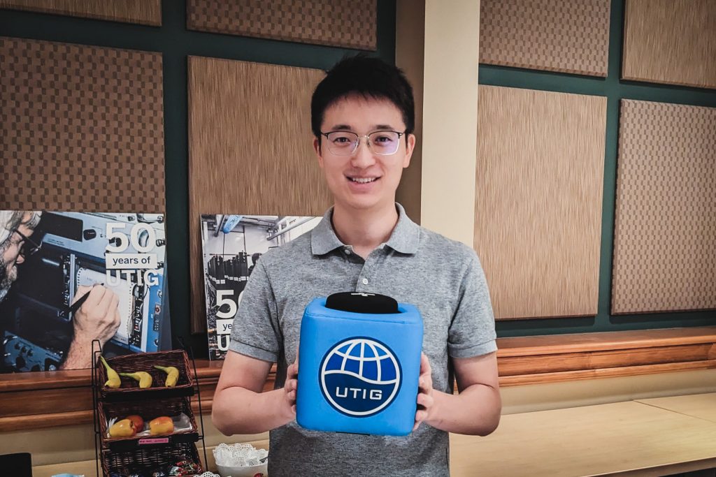 Photo of Jingxuan Wei holding the UTIG cube in the seminar room.