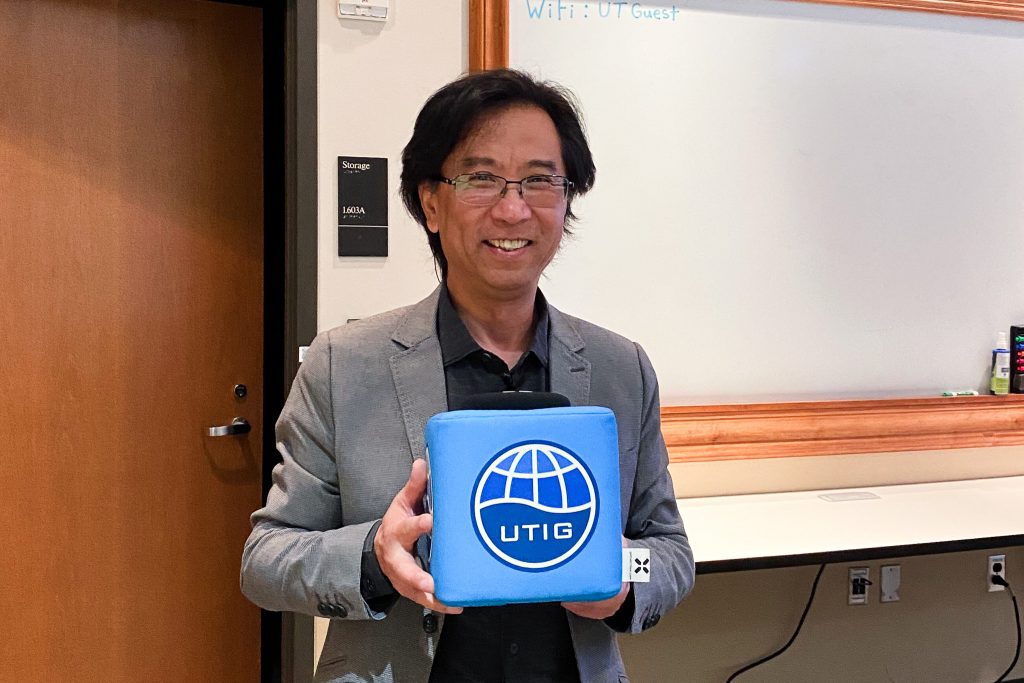 Photo of Ping holding the UTIG cube in the seminar room.