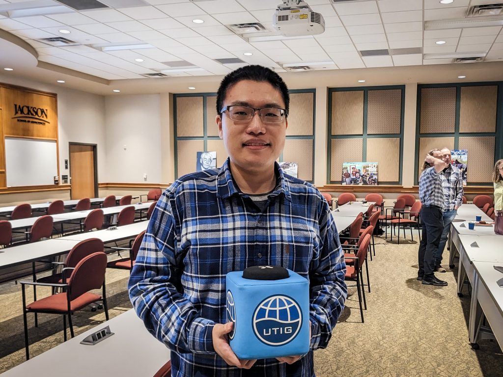Photo of Shuo holding the UTIG cube in the seminar room.