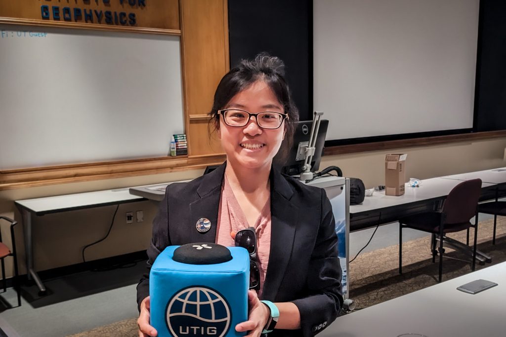 Photo of Xinting Yu holding the UTIG cube in the seminar room.