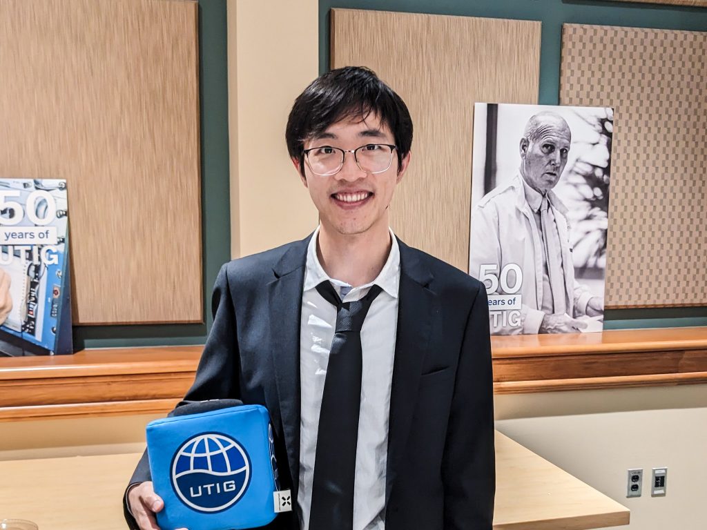 Photo of Zhe holding the UTIG cube in the seminar room.