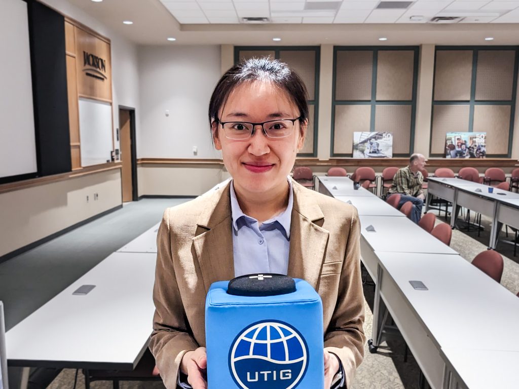 Photo of Hingyu holding the UTIG cube in the seminar room.