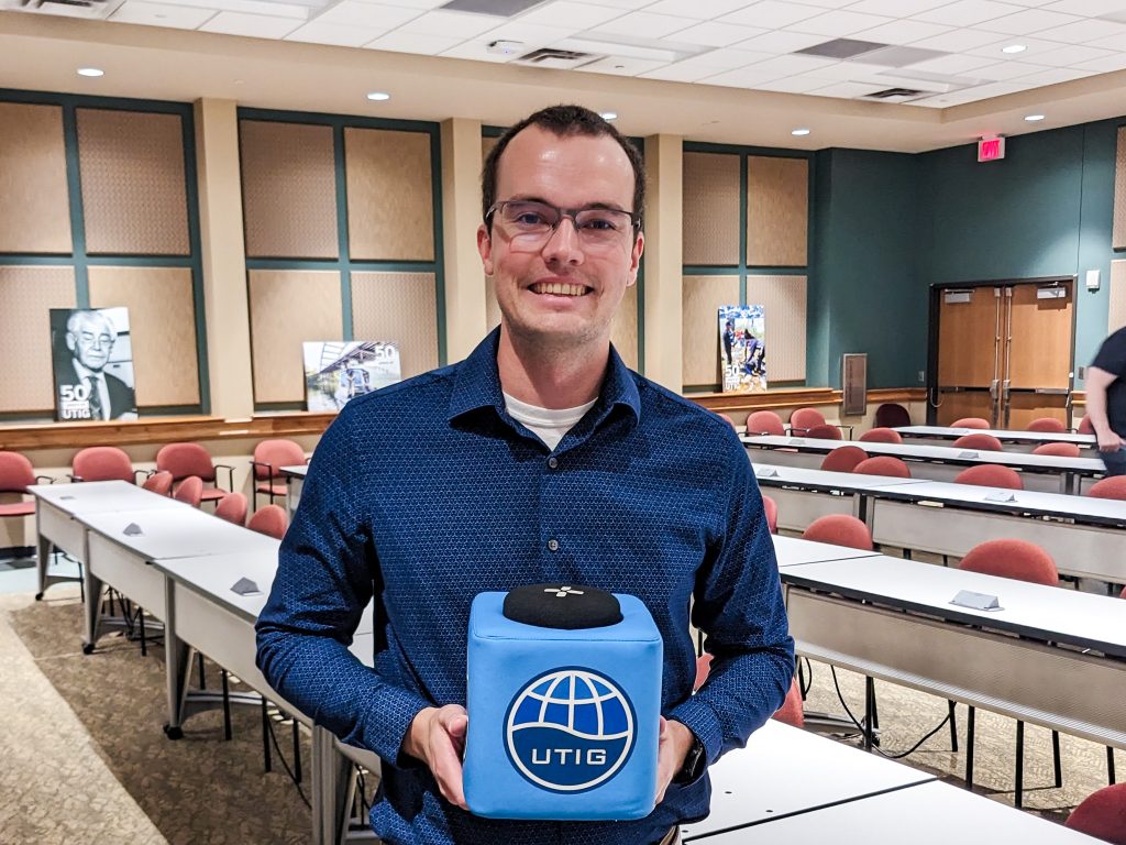 Photo of Will holding the UTIG cube in the seminar room.