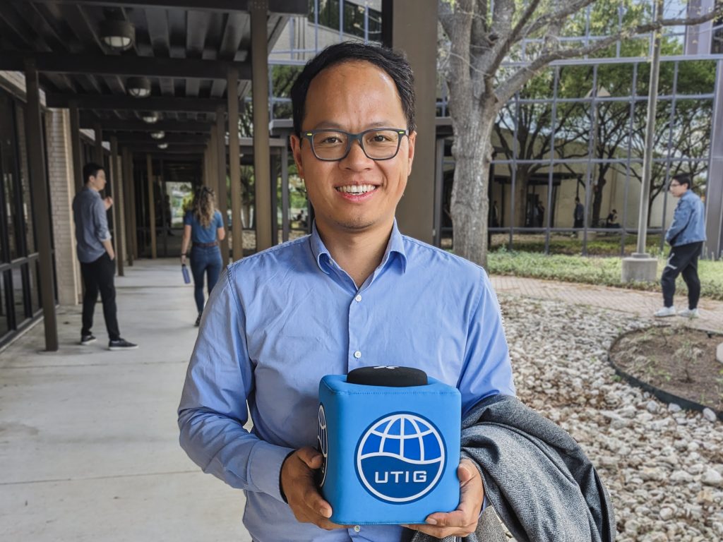 Photo of Zhongwen holding the UTIG cube outside in the courtyard by the seminar room.