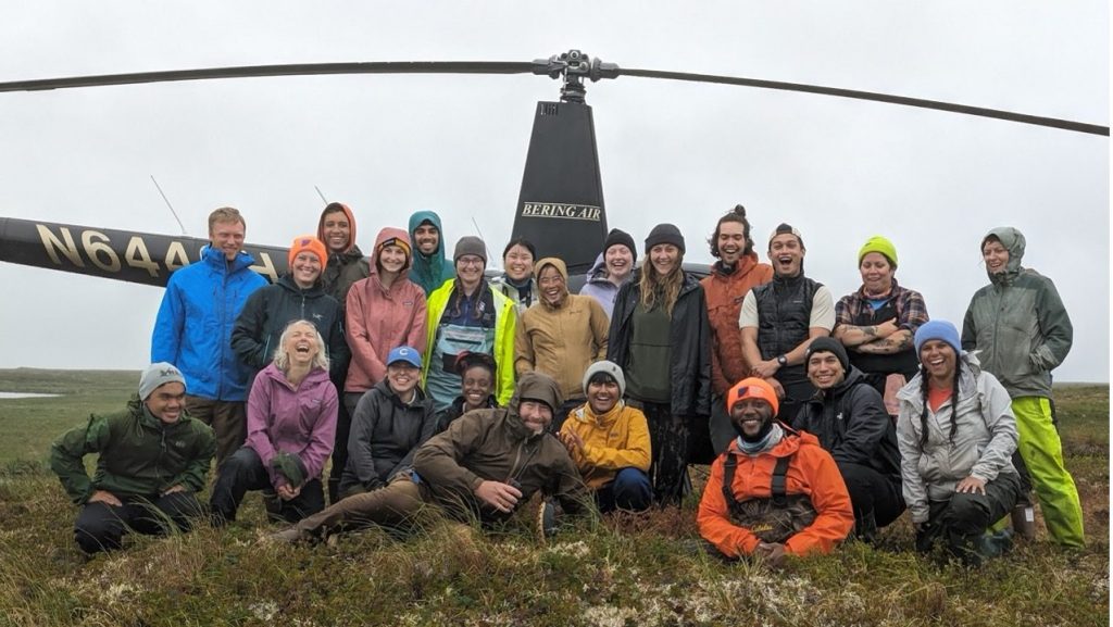 The group poses for a photo in front of a helicopter