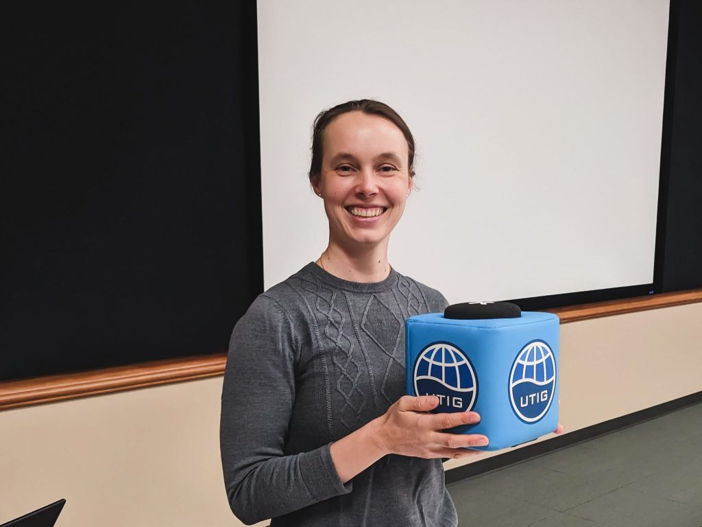 Photo of Cornelia holding the UTIG cube of truth in the UTIG Seminar room.