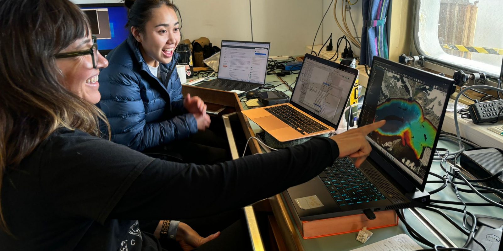 Photo of the scientist looking excitedly at and pointing at a laptop screen showing mission science.
