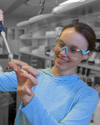 Photo of Cornelia Rasmussen wearing safety goggles and using a pipette in a lab.