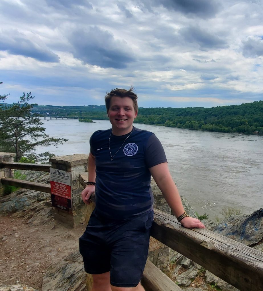 Picture of Hunter standing in front of a fence looking out to lake in a park.