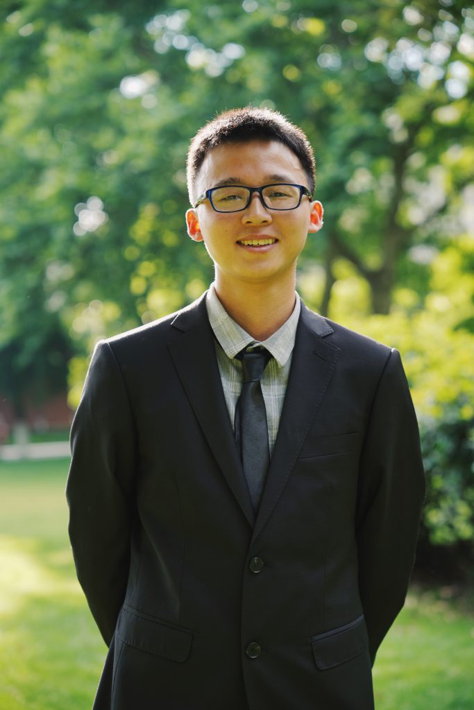 Portrait of Xiang in front of some trees.