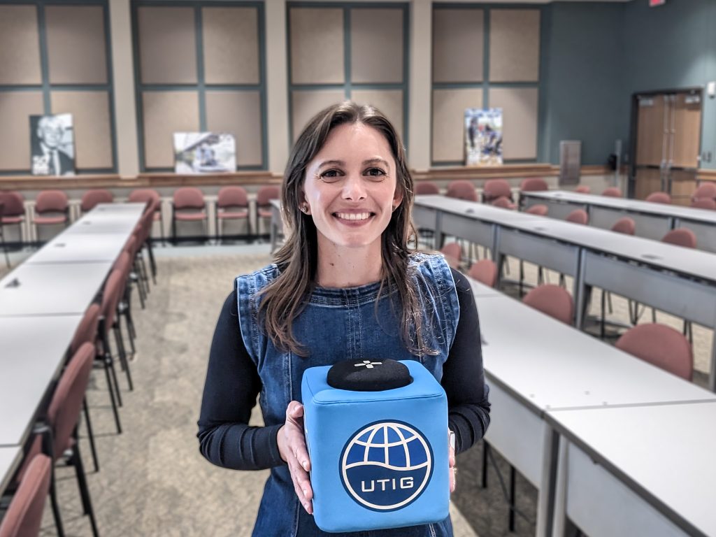 Photo of Brandee holding the UTIG Cube of Truth in the UTIG seminar room.