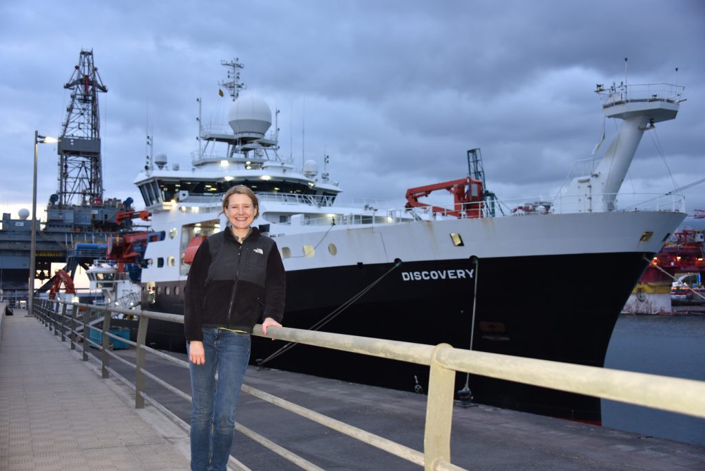 Photo of Kate standing in front of a ship.