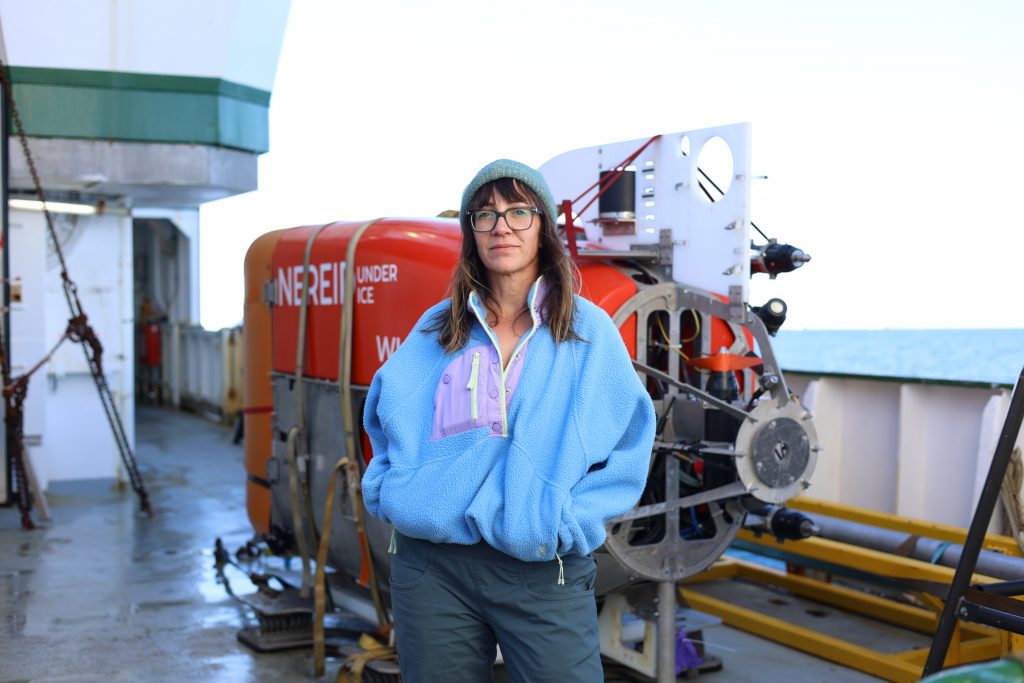 Photo of Ginny in front of Nui on the deck of the vessel. NUI is strapped down.