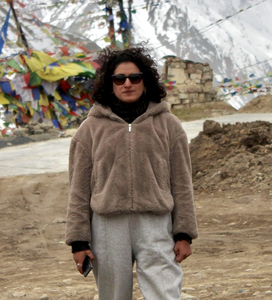 Photo of Shivangini standing in front of a colorful tent by a mountain.