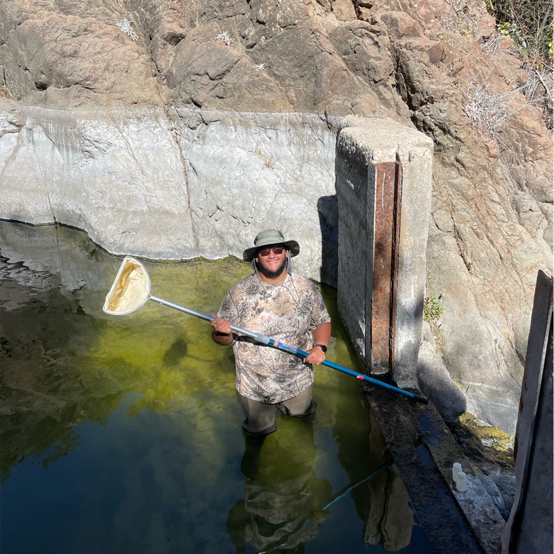 Photo from above of Enrique wading in water holding a net