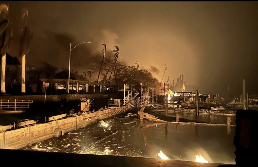 Photo of a burned dock at night with fires burning in the distance