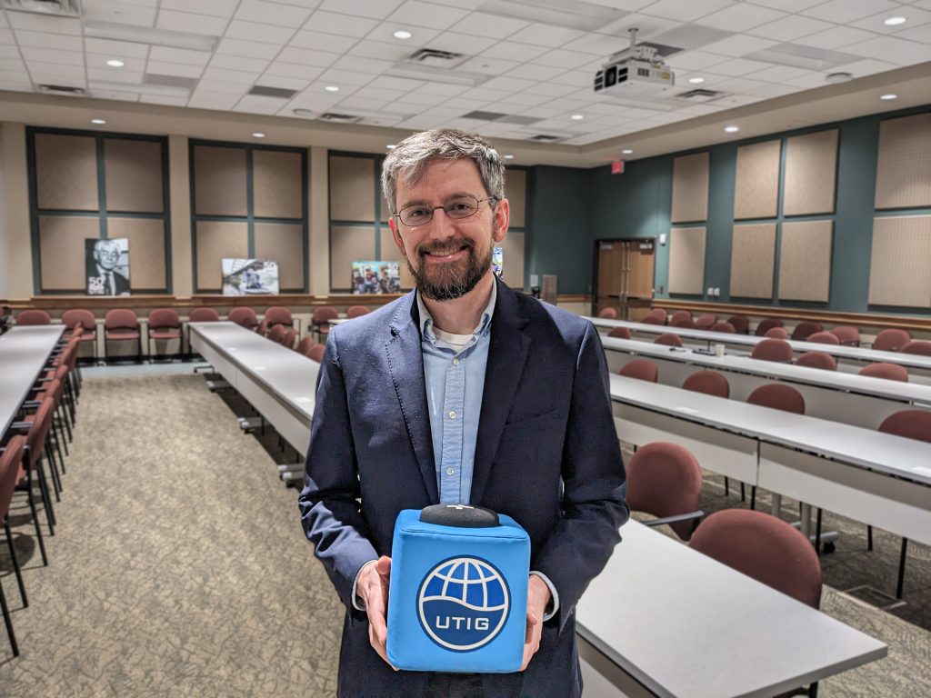 Picture of Peter holding the UTIG Cube of Truth in the UTIG seminar room.